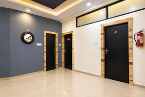 A hallway with three doors, each with a number above it, and a fire extinguisher mounted on the wall. - Fabhotel Shivom (Indore)