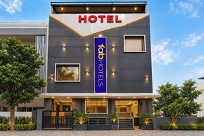 A modern hotel building with a prominent 'HOTEL' sign, a vertical 'Hab Hotels' sign, and a well-lit entrance with steps leading to the door. - Fabhotel Shivom (Indore)
