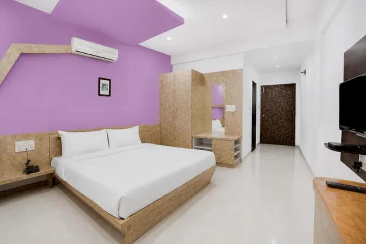 Un dormitorio moderno con una cama, mesitas de noche, un televisor y un baño a la vista al fondo.