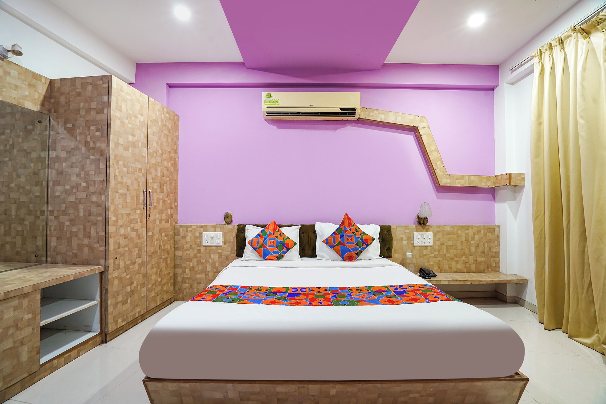 A bedroom with a bed, a wardrobe, an air conditioning unit, and a mirror.