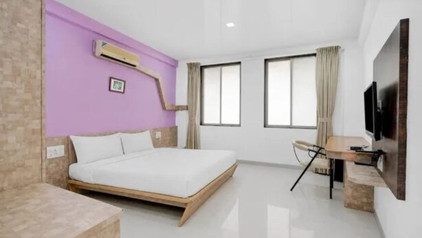 Una habitación de hotel moderna con cama, escritorio, televisor y ventana.