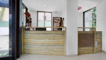 A reception desk with a wooden finish, a large window, and a statue on the counter.
