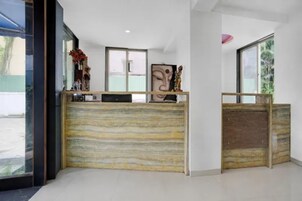 Una recepción con mostrador de madera, un ventanal amplio y una estatua sobre el mostrador.