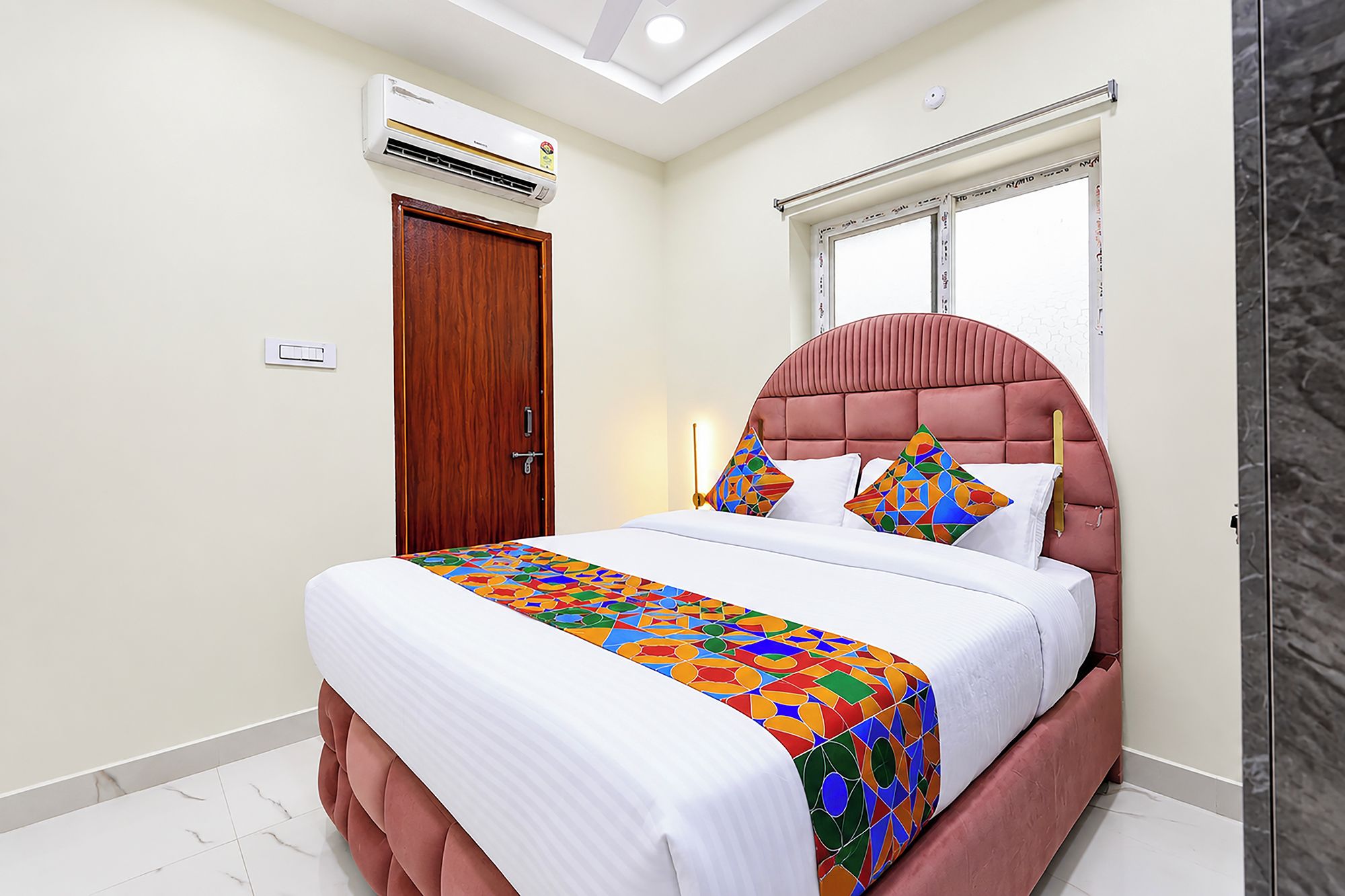 Quarto com cama, janela, porta e ar condicionado.