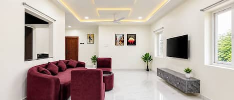 A modern living room with a sectional sofa, a flat-screen TV, and a ceiling fan.