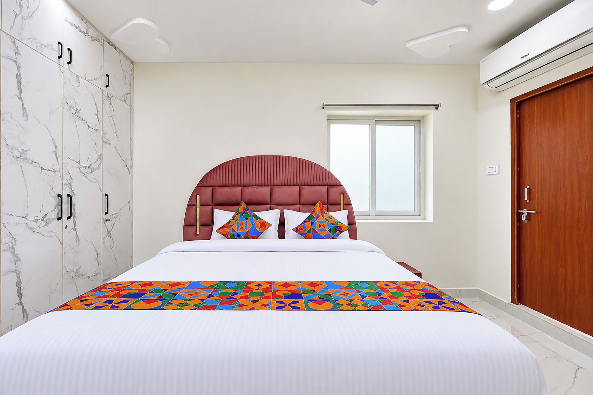 Un dormitorio con cama, armario, ventana y equipo de aire acondicionado.