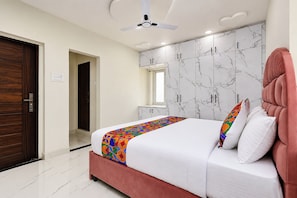 A bedroom with a bed, a ceiling fan, a wardrobe, and a door.