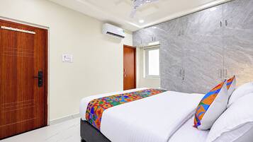 Quarto de hotel com cama, ventoinha no teto, parede de mármore e porta de madeira.