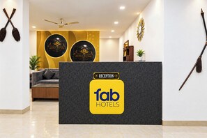 A reception desk with a sign for 'fab hotels' and a reception area with a sofa and a ceiling fan. - FabHotel Casa Stay (New Delhi)
