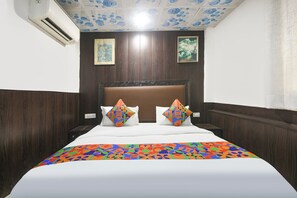 A hotel room with a bed, two pillows, a headboard, and a ceiling with floral patterns. - FabHotel Casa Stay (New Delhi)