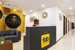 A hotel reception area with a reception desk, a sofa, a clock, and a wall-mounted decorative piece. - FabHotel Casa Stay (New Delhi)