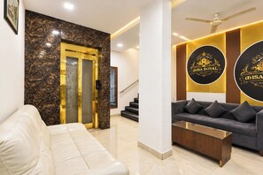 Un vestíbulo de hotel con una pared de mármol, un sofá, una mesa de centro y una escalera.
