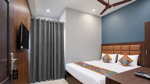 Una habitación de hotel con una cama, un escritorio, un televisor y un ventilador de techo.