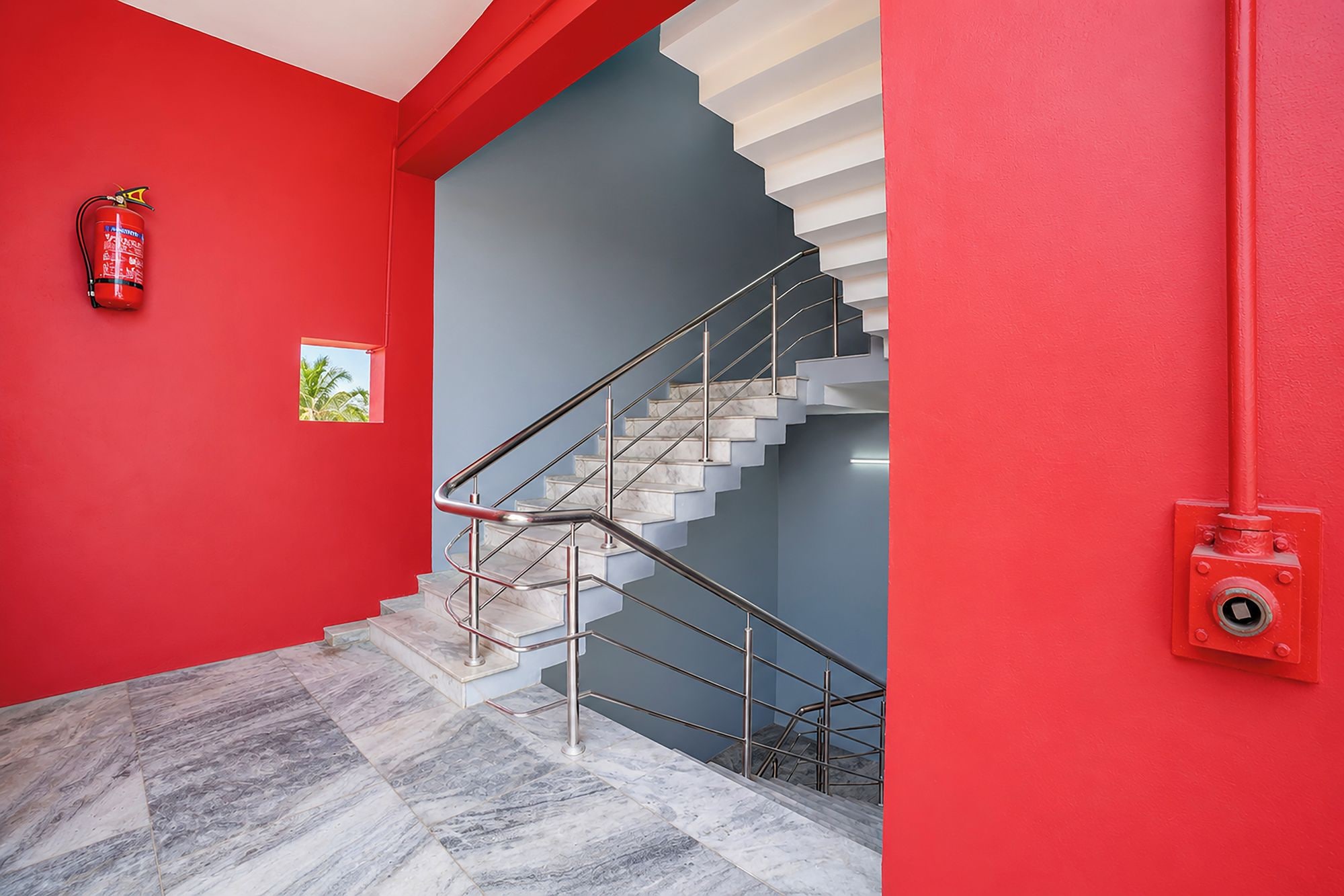 Eine Treppe mit einer roten Wand und einem Feuerlöscher auf der linken Seite.