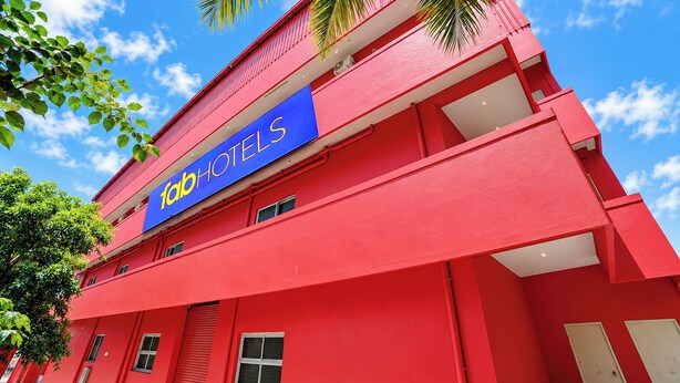 Un edificio rojo con un letrero azul que dice 'fabHOTELS' y varias ventanas.
