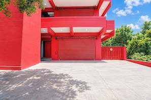 Un edificio moderno con fachada roja, una puerta de garaje cerrada y un camino de entrada pavimentado.