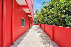 A red building with a long corridor and a tree-lined path.