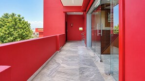 Pasillo exterior rojo con puerta de vidrio que da a una escalera.