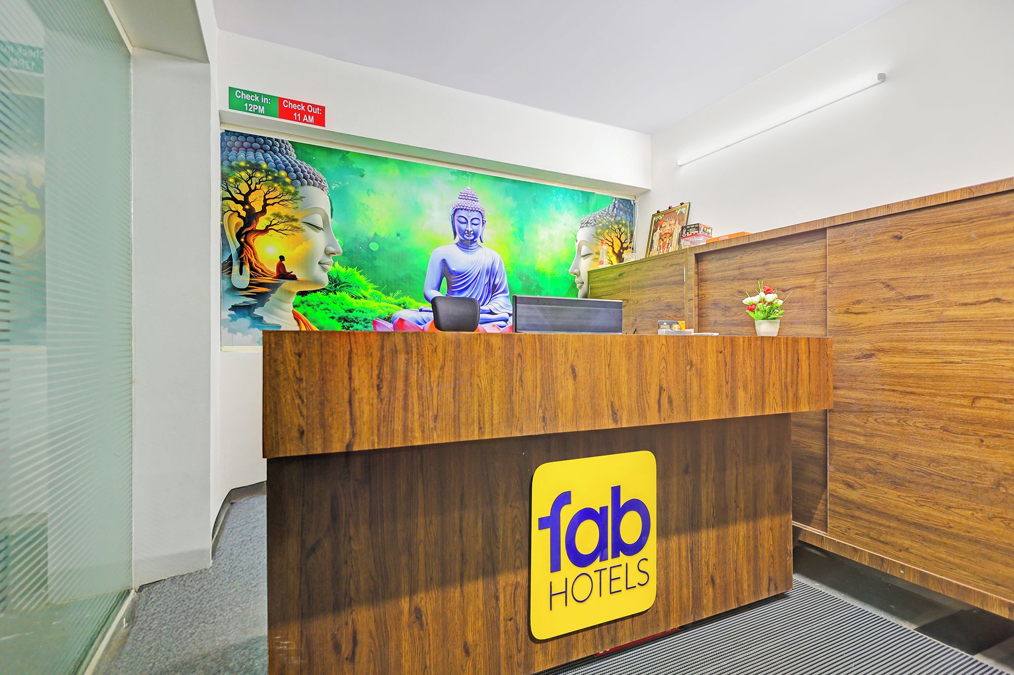 Un mostrador de recepción de hotel con una estatua de Buda y un letrero de registro de entrada/salida.