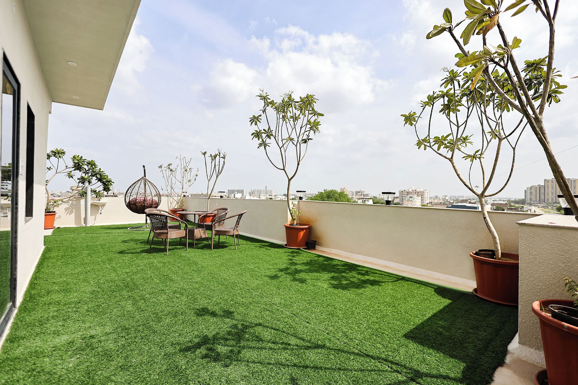 Eine Dachterrasse mit Kunstgrasanlage, Topfpflanzen und einem Essbereich.