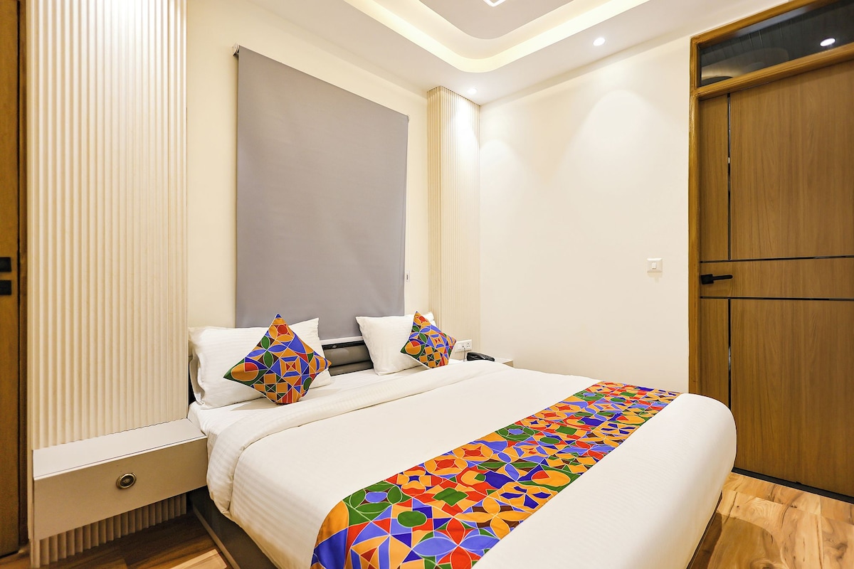 Una habitación de hotel con cama, mesita de noche, armario de madera y ventana con persianas.