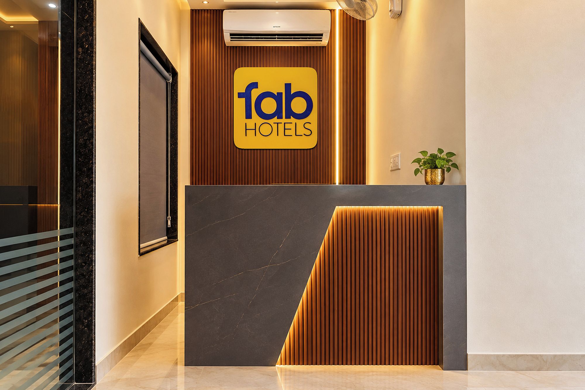 A reception area with a 'fab hotels' sign, a wooden panel design, and a marble floor.