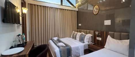 A hotel room with two beds, a desk, a chair, a television, and an air conditioning unit.