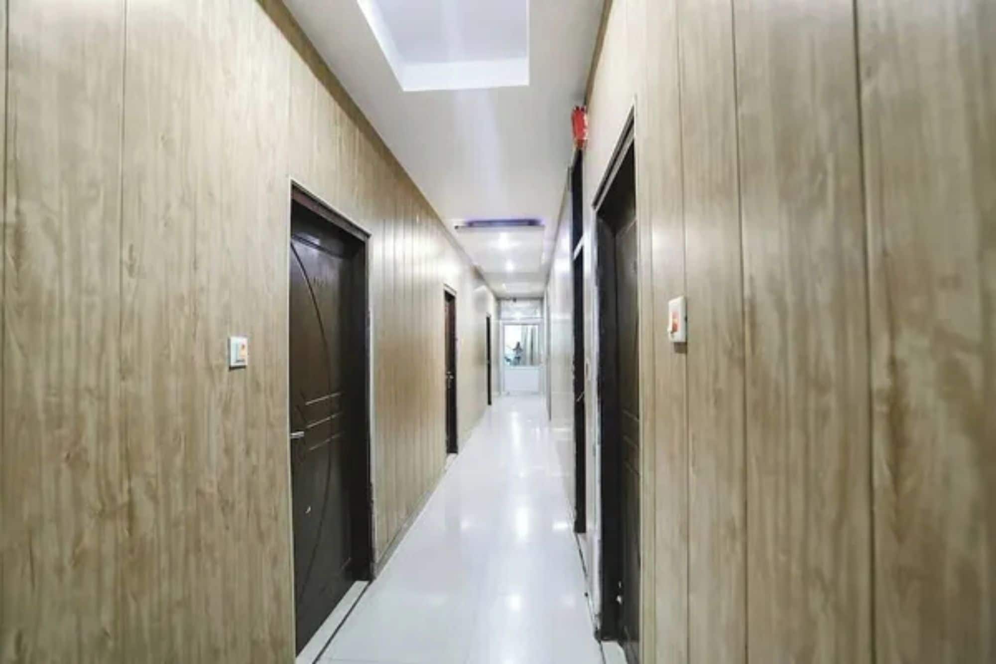Un pasillo con paredes de paneles de madera y piso de baldosas, que conduce a una puerta al final.