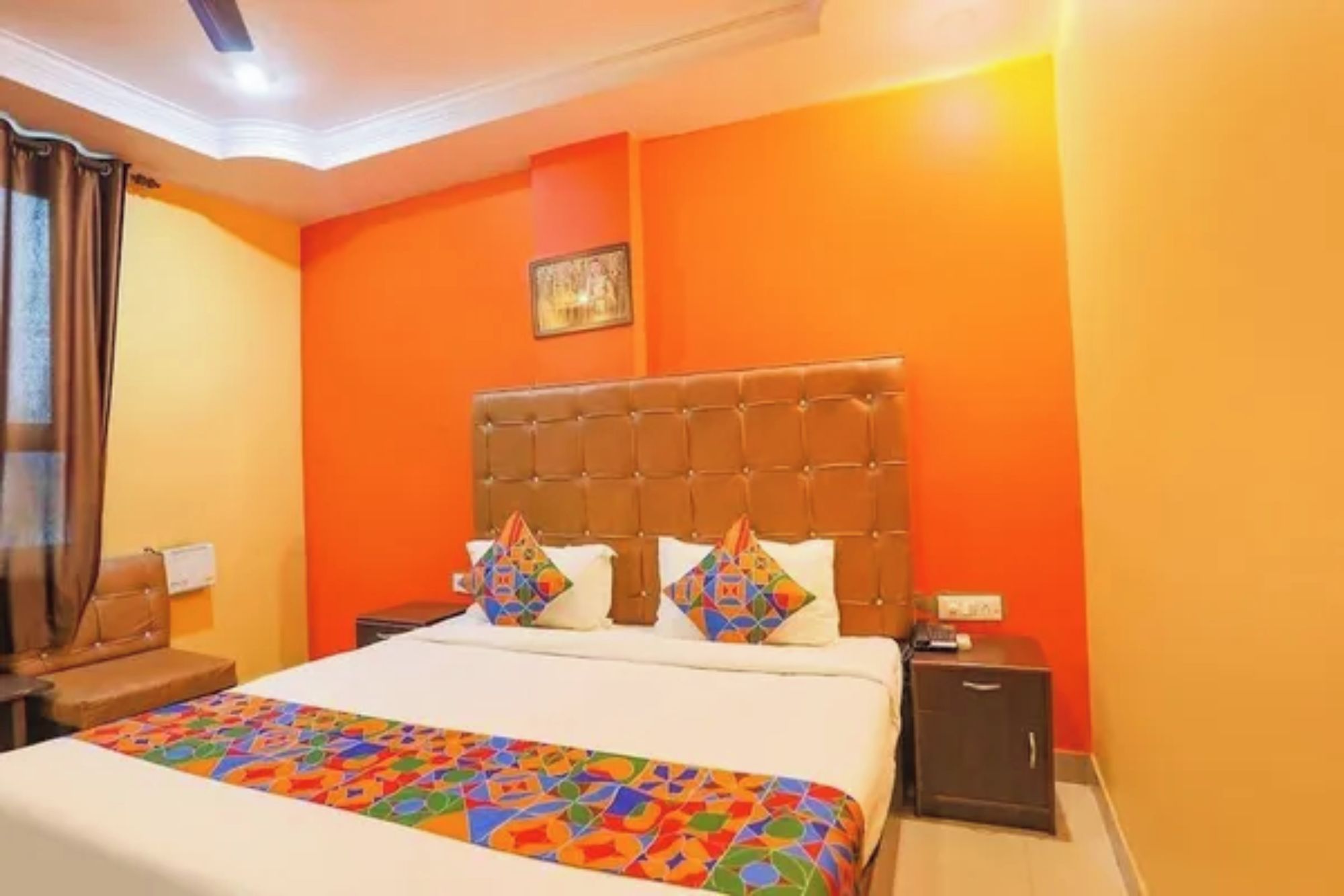 A hotel room with a large bed, orange walls, and a tufted headboard.