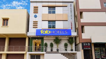 A multi-story hotel with a prominent 'fabHOTELS' sign, a visible entrance, and a staircase leading to the entrance.