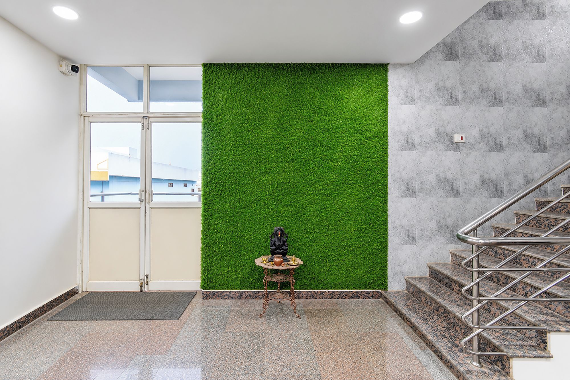 Una habitación con una pared verde, una pequeña mesa con objetos y una escalera.