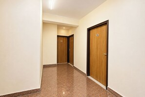 A corridor with polished stone flooring and wooden doors, each marked with a number. - FabHotel Royal Inn Ii (New Delhi)
