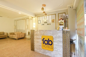 A reception desk with a logo for Fab Hotels, a clock, and a framed Buddha statue. - FabHotel Royal Inn Ii (New Delhi)