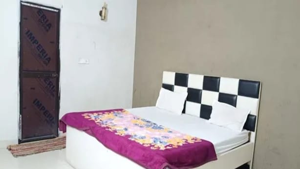Una cama individual con un cabecero a cuadros, una colcha de flores moradas y un colchón blanco.