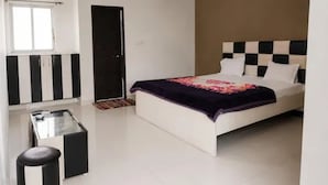 Un dormitorio con cama, armario, mesita y cubo de basura.