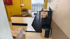 Una habitación pequeña y funcional con un escritorio, un cesto de basura y una silla con funda estampada.