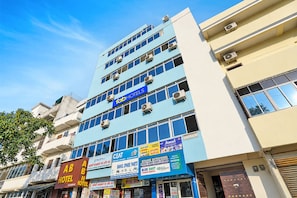 Un edificio de varios pisos con diversos comercios en la planta baja, incluyendo un hotel y varias tiendas.