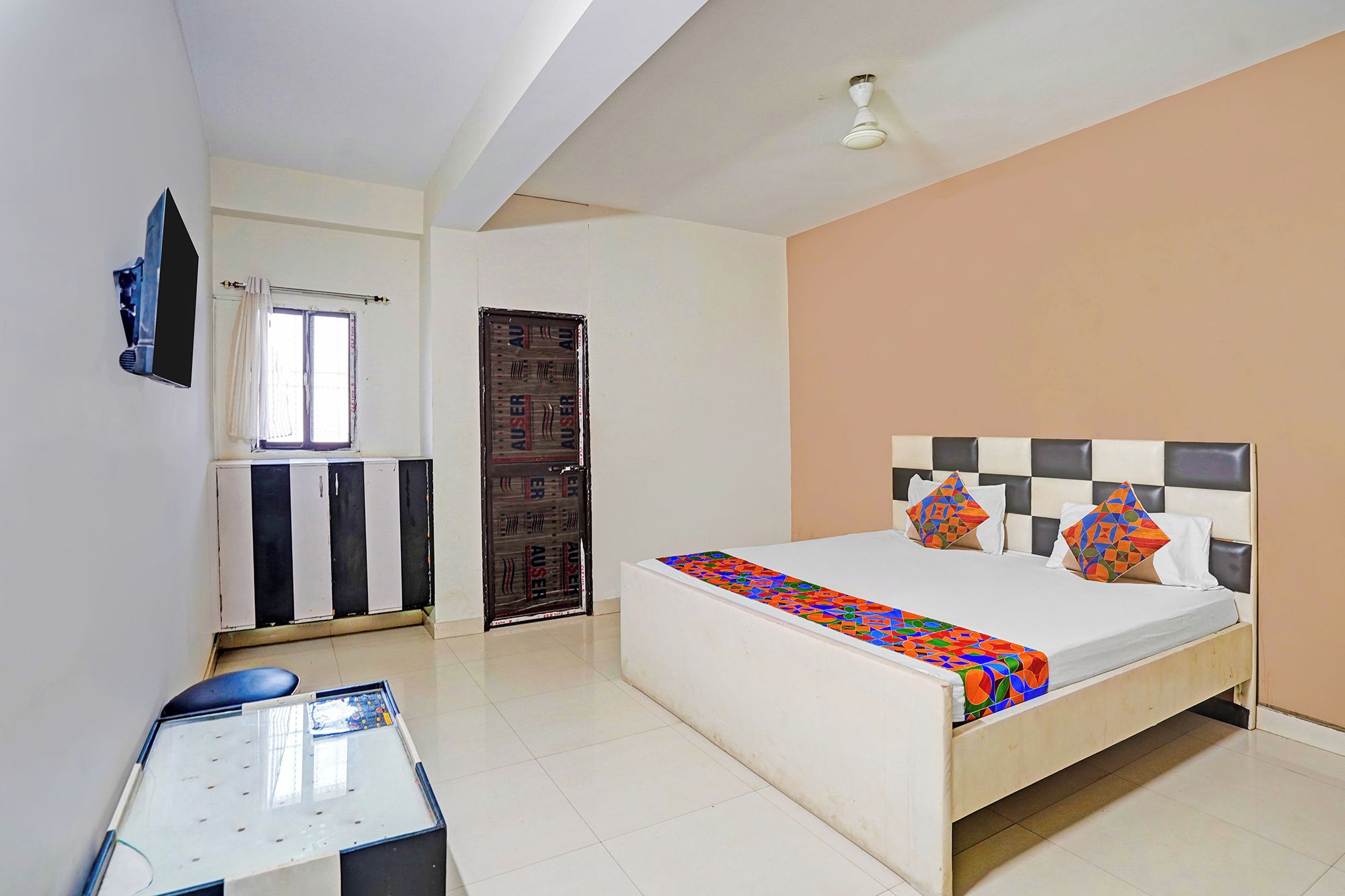 Un dormitorio con cama, escritorio, ventana y puerta.
