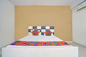 Una habitación de hotel con una cama, cabecera con diseño geométrico y pared lisa.
