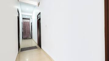 A narrow hallway with a tiled floor, a door on the right, and a curtain at the end.