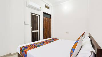 A bedroom with a bed, a wardrobe, and an air conditioning unit.