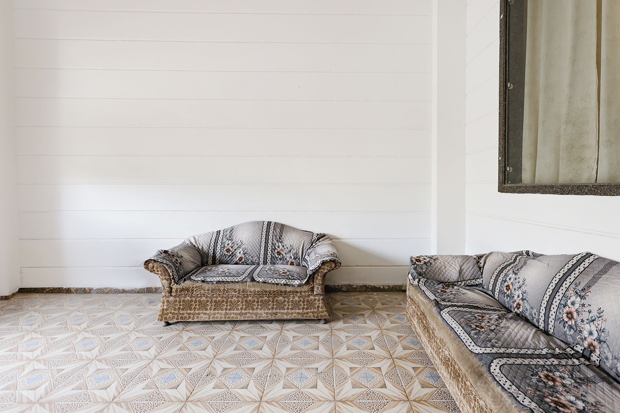 Una habitación de esquina con piso estampado, un sofá y una silla.