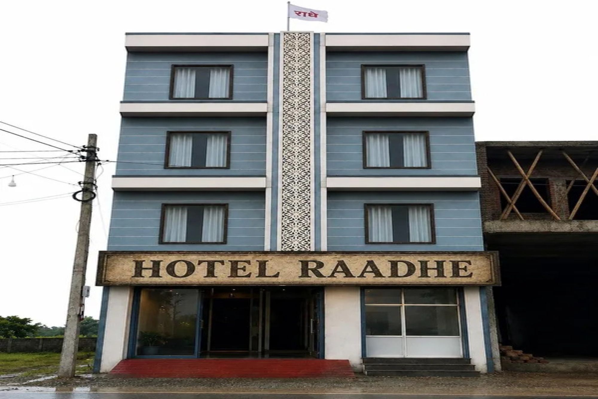 Ein mehrstöckiges Gebäude mit einem Schild, auf dem 'HOTEL RAADHE' steht, am Eingang.