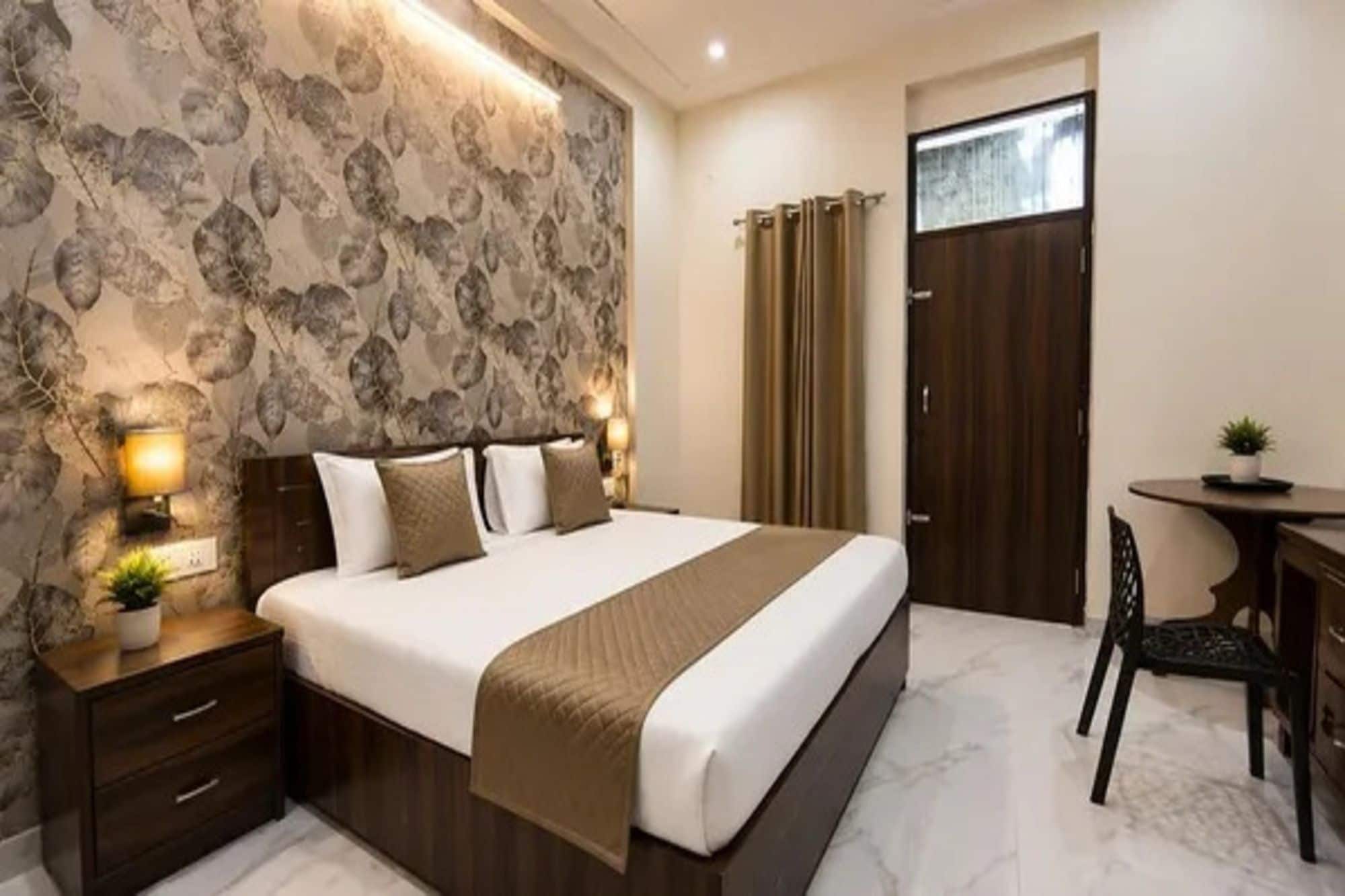 Ein Hotelzimmer mit einem großen Bett, Nachttischlampen, einem Schreibtisch mit Stuhl und einer Tür mit Vorhängen.