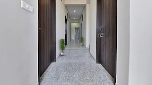 A hallway with dark wooden doors, a potted plant, and a light switch on the wall. - Fabhotel Raadhe (Khatoo)