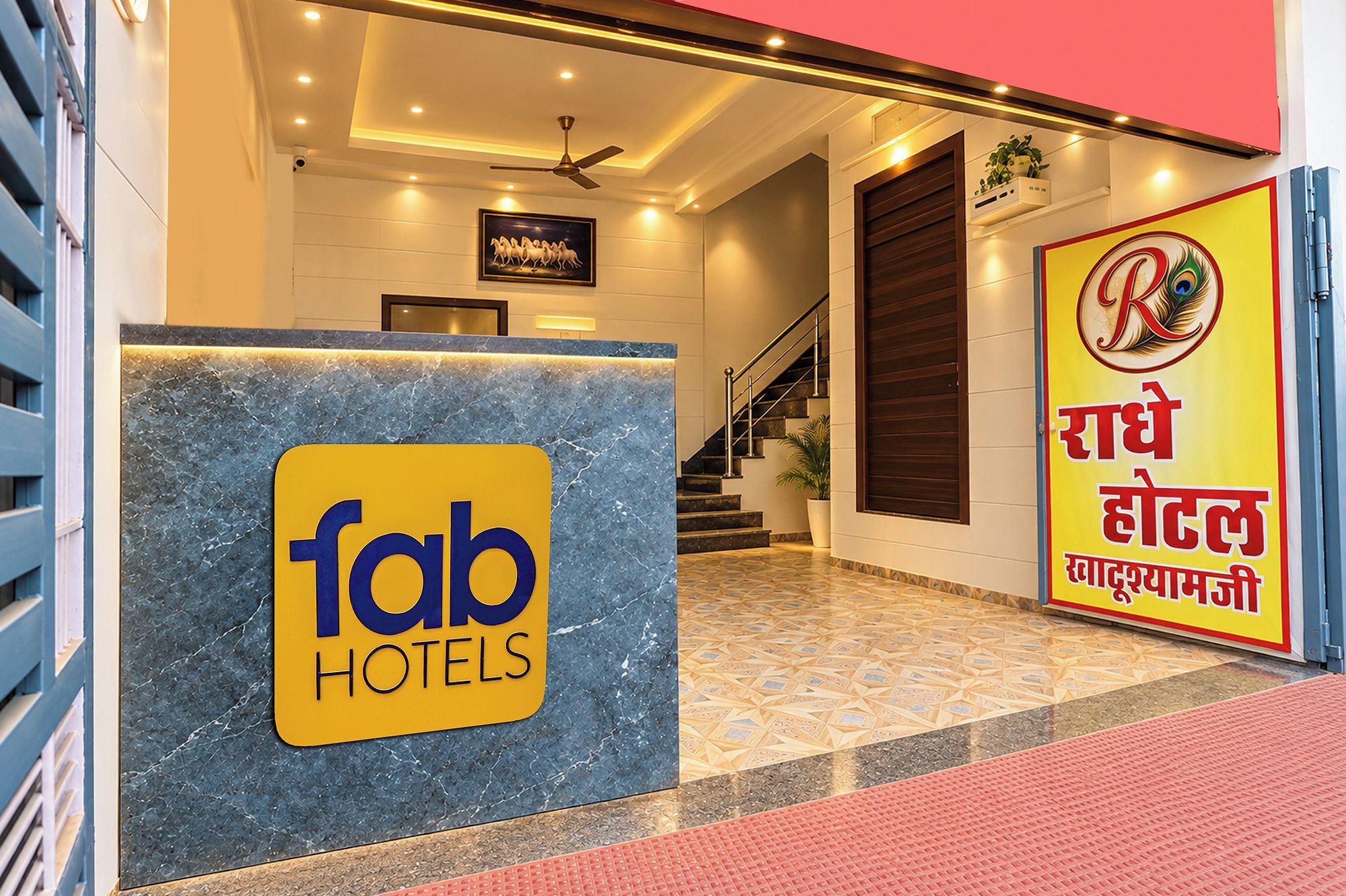 Recepção de hotel com balcão de mármore, escada e placa de identificação.