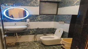 Un baño con inodoro, lavabo y espejo con luz circular.