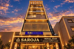Un hotel con un llamativo letrero que dice 'Saroja Royal Stay', indicando una experiencia de lujo.