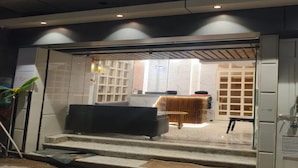 Un interior moderno con una escalera que conduce a una zona de estar y una cocina visible a través de un separador de vidrio.