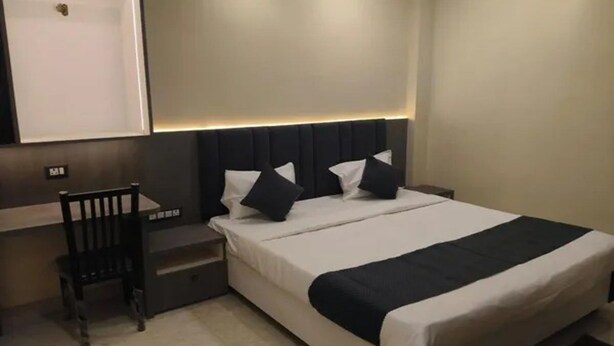 Una habitación de hotel con cama, mesita de noche y una silla.